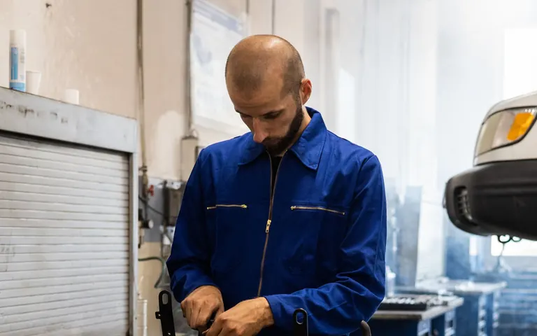 Automotive mechanic inspecting and repairing an engine in a workshop