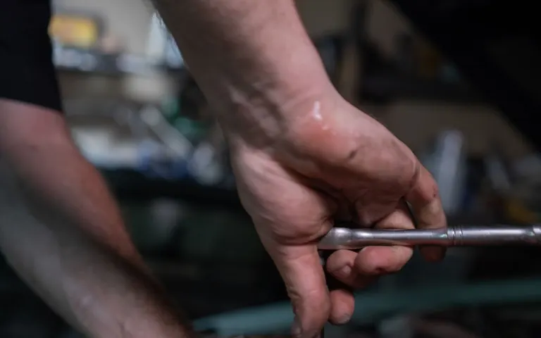 Mechanic using a hand tool while preparing an automotive engine