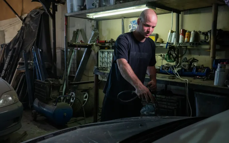 Automotive mechanic inspecting a vehicle engine in a service garage